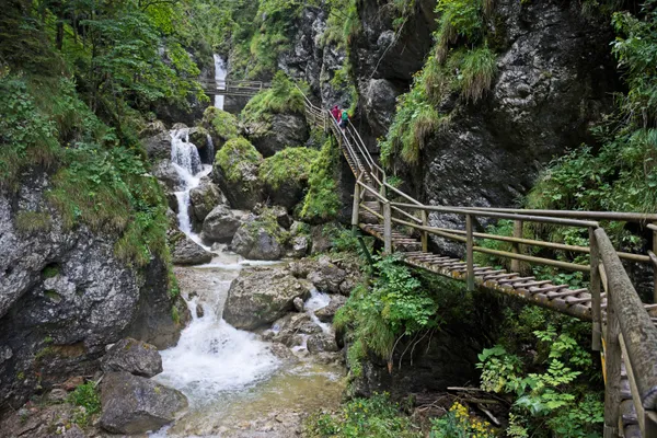 Holzsteg entlang der Felswand in der Bärenschützklamm mit Wasserfall