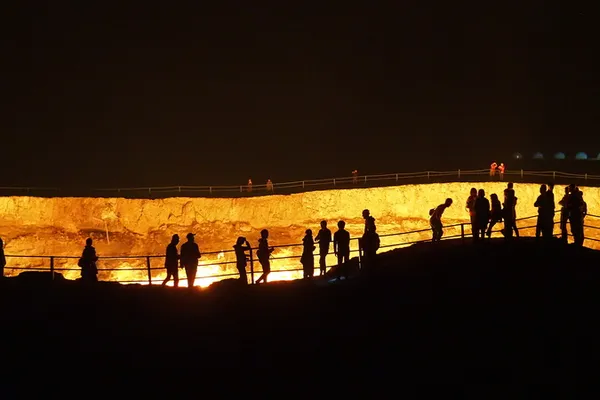 Besucher am Rand des Feuerkraters von Darwaza bei Nacht